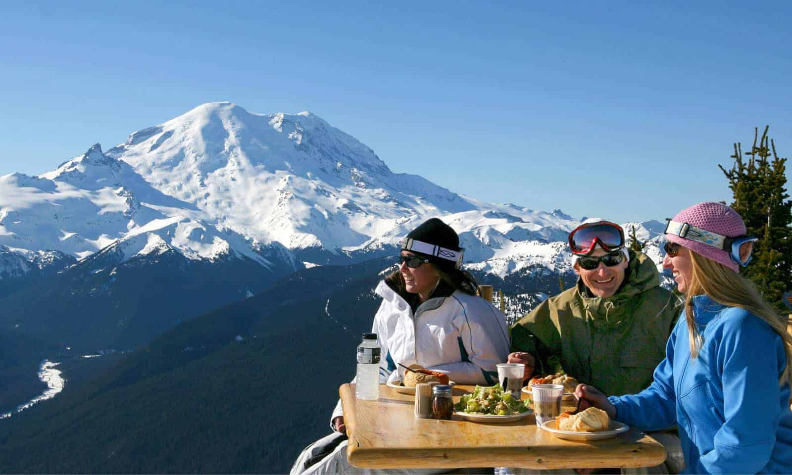A group of people dining outdoors with a view of Mt Rainier