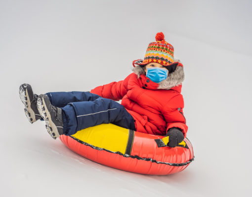 girl tubing on snow wearing a mask
